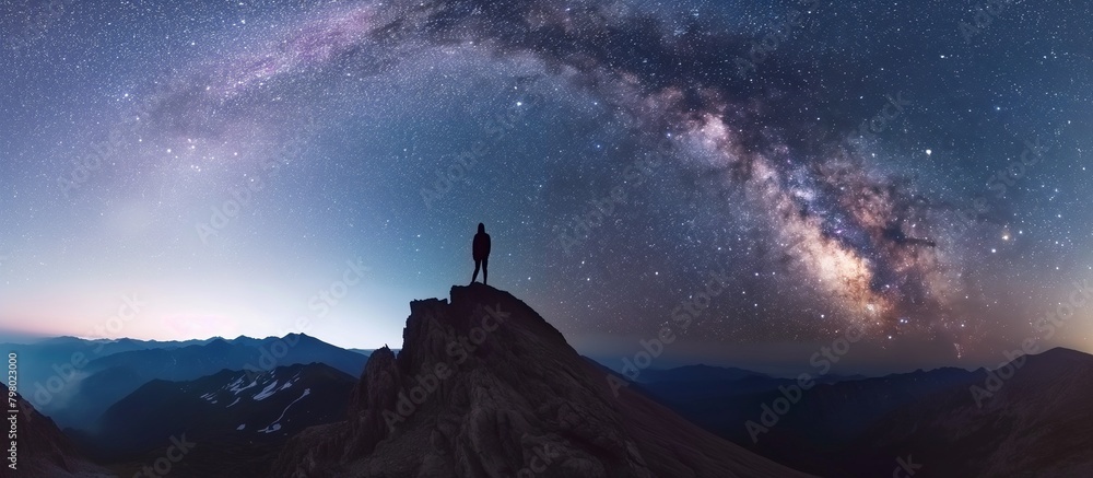 Milky Way arch and man on the mountain peak at starry night. Silhouette of alone guy, blue sky with bright stars in summer. Galaxy in the starry sky. Beautiful summer night in the mountains. Milky Way arch and man on the mountain peak at starry night. Silhouette of alone guy, blue sky with bright stars in summer. Galaxy in the starry sky. Beautiful summer night in the mountains.
