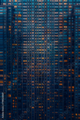 cityscape of american apartment building during twilight, outside wall, big city, skyscrapers, dark blue and grey atmosphere, many warm lighting from inside, portrait format, photorealistic // ai-gene