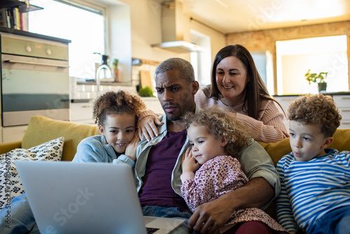 Family using laptop together on the couch at home
