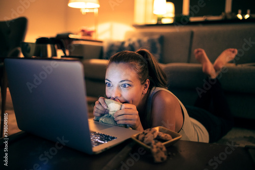 Woman watching movie on laptop with snacks at night photo