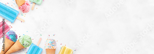 Assorted colorful pastel ice cream cones and popsicle summer frozen desserts. Top view corner border on a white marble banner background. Copy space.