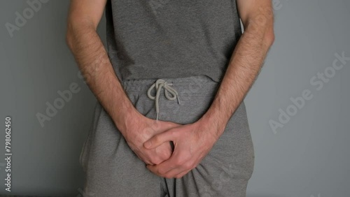 A man with prostate disease holds his hands in the groin area.