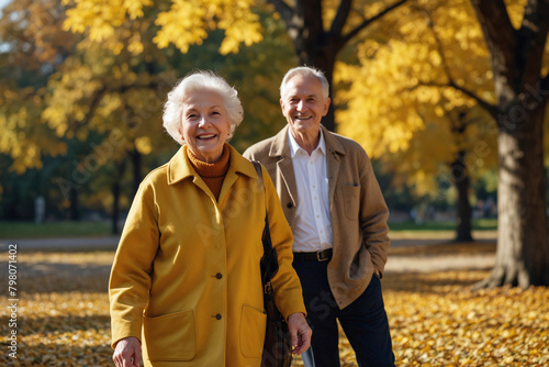 Pensioners, an elderly husband and wife in a sunny autumn park. Yellow maple leaves are falling from the sky.