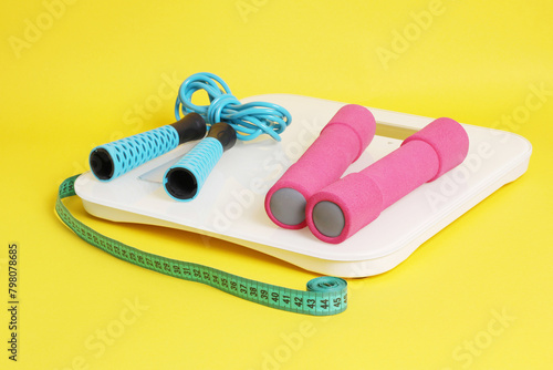 Scales, jump rope, meter, dumbbells on a yellow background