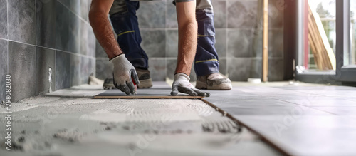 A uniformed construction worker laying ceramic tiles on a wall. Tiler, repair in the apartment, private master.