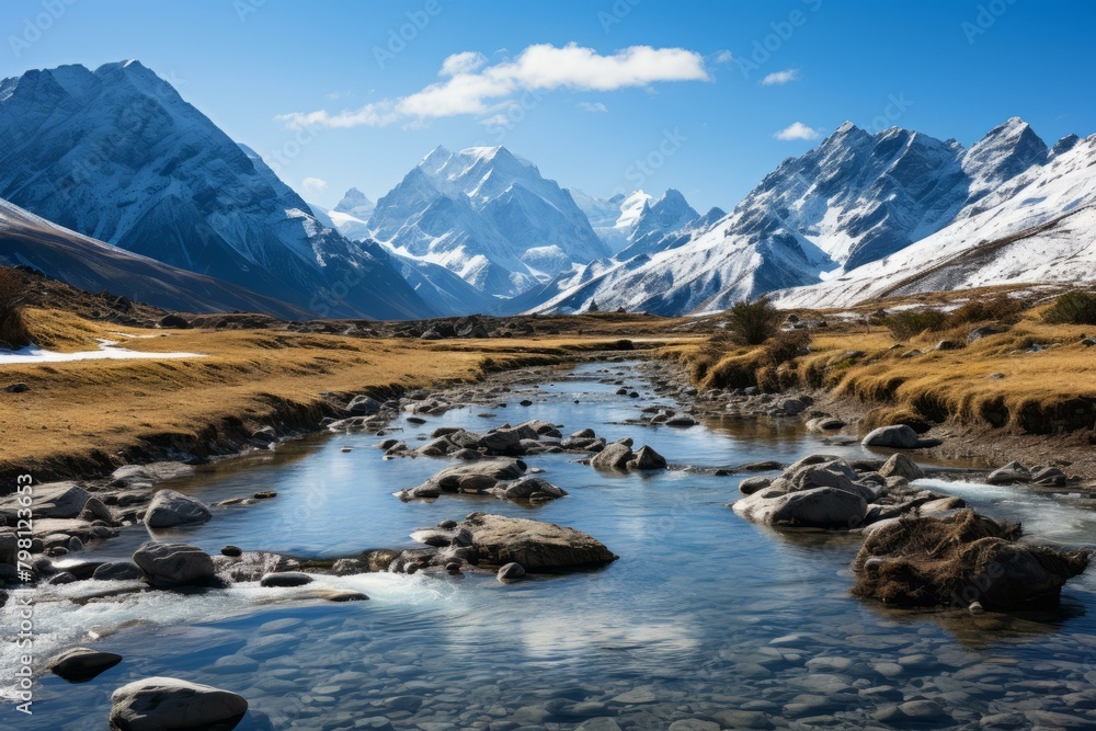 b'Mountain river flowing through a valley with snow capped mountains in the distance'