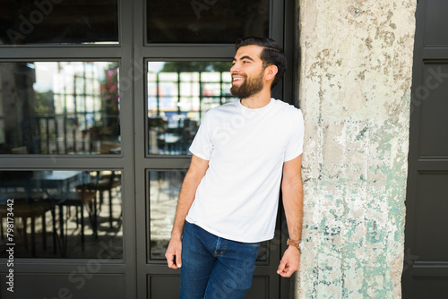 Good looking hispanic man in a white t-shirt ready for branding mock-up, standing outdoors with a joyful expression © AntonioDiaz
