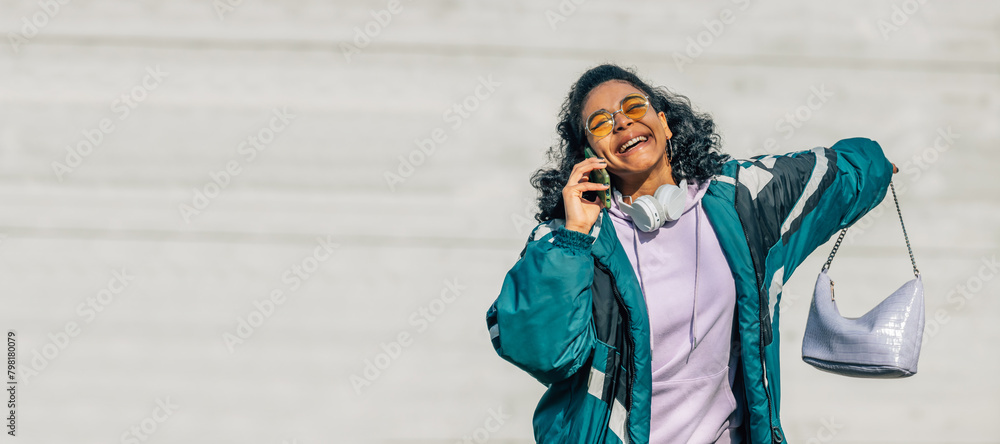 Young woman with vintage style talking by mobile phone in the street