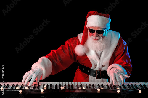 Santa Claus playing the electric piano in a nightclub at a Christmas and New Year party or Corporate events. Senior piano player as Santa at a concert, festival, or celebration
