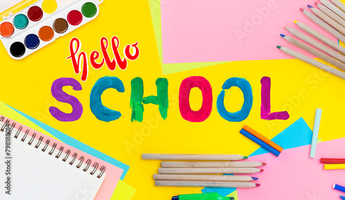 Hello school background. Top view flat lay concept. Childish lettering, colored paper, supplies, stationery for primary school, elementary school or grade school, kindergarten or preschool educational