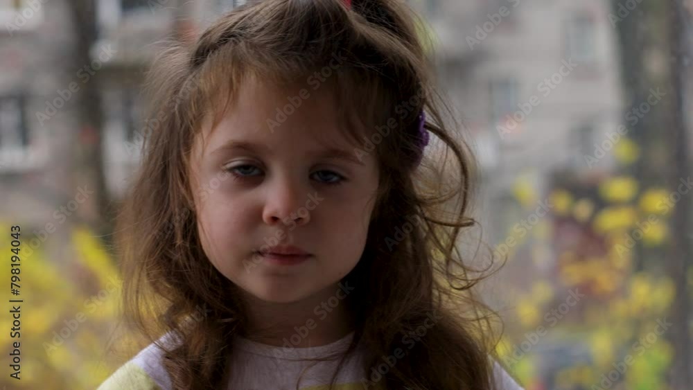 A little girl is sitting by the window A little girl is sitting by the window