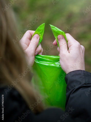 A woman tying a green dog poop bag