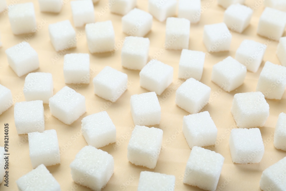 White sugar cubes on beige background, closeup White sugar cubes on beige background, closeup
