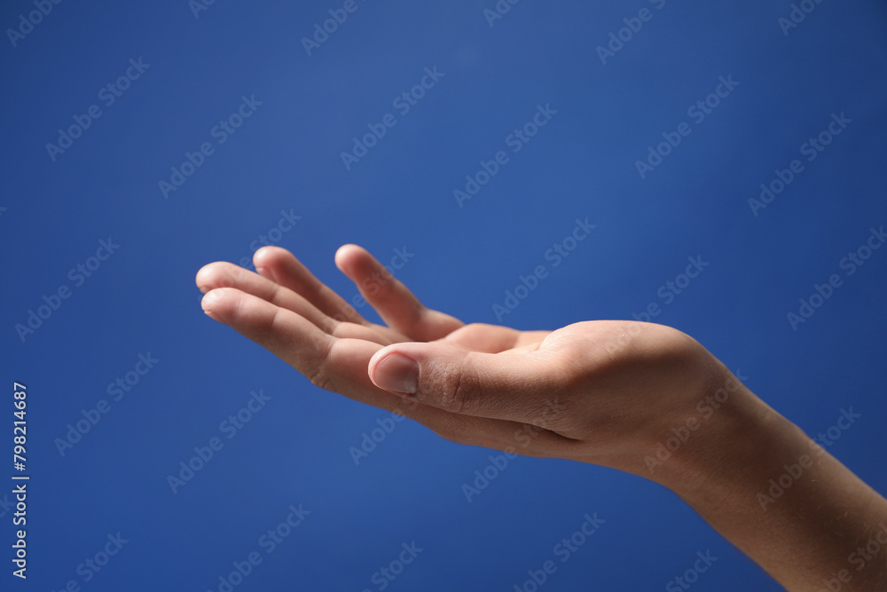 Man holding something in hand on blue background, closeup Man holding something in hand on blue background, closeup