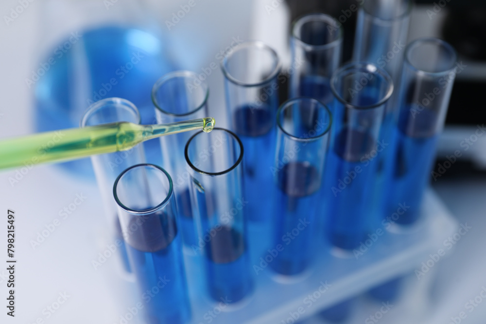 Laboratory analysis. Dripping liquid into test tubes on white table, closeup Laboratory analysis. Dripping liquid into test tubes on white table, closeup