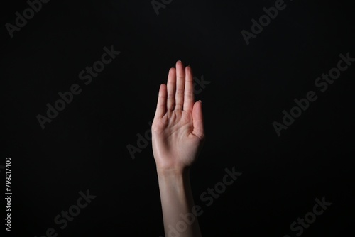 Woman showing open palm on black background, closeup © New Africa