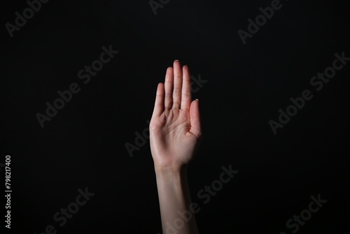 Woman showing open palm on black background, closeup