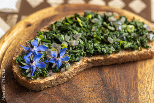 Fresh borage and blue flowers delicately garnish a crispy bread slice