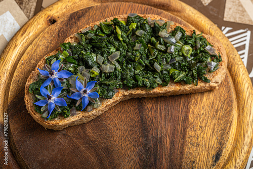 A slice of crunchy bread, elegantly decorated with fresh borage and blue flowers