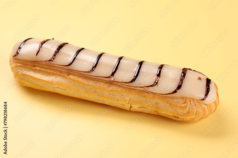 Delicious eclair covered with glaze on yellow background Delicious eclair covered with glaze on yellow background