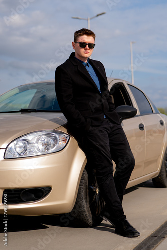 Young handsome man in suit at his beautiful car.A guy in a suit and sunglasses © Robert
