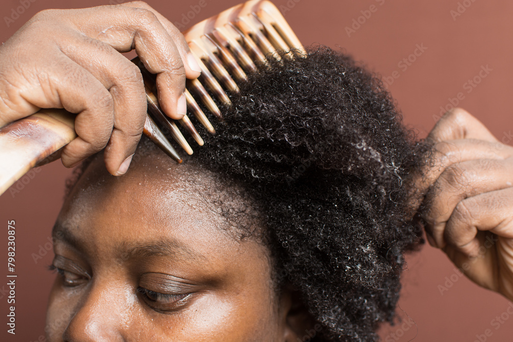 Combing black afro curly hair with shrinkage, using a wide tooth comb to detangle wet Type 4c hair Combing black afro curly hair with shrinkage, using a wide tooth comb to detangle wet Type 4c hair