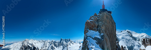 Haute-Savoie, France, 04-25-2024: blue sky and panoramic view of L’Aiguille du Midi (Needle at midday), the highest spire (3.842 m) of the Aiguilles de Chamonix, with the Mont Blanc massif peaks 
