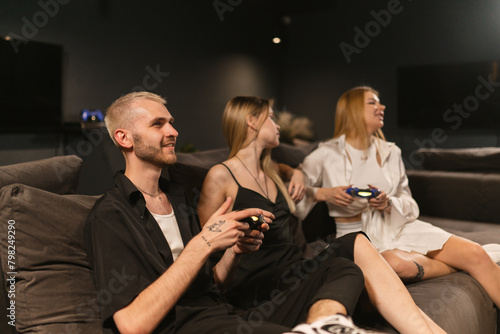 Group of ladies along with gentleman spend times in game room. Woman and man compete enthusiastically playing video games