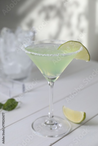 Delicious Margarita cocktail in glass and lime on white wooden table