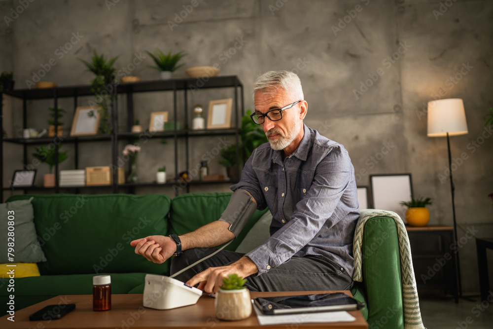 One mature man with eyeglasses measure blood pressure at living room One mature man with eyeglasses measure blood pressure at living room