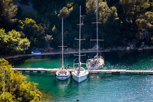 Sailing boats anchored in the Krka river estuary in the close porximity of the town of Skradin, Croatia, hidden by the steep, forest covered cliffs photo