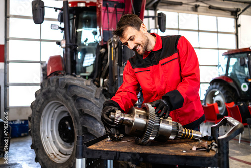 Mechanic repairing and servicing transmission for tractor agricultural machine. photo