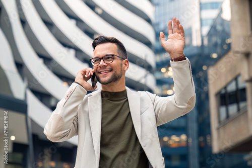 Shot of a young businessman using a smartphone and waving against an urban background.