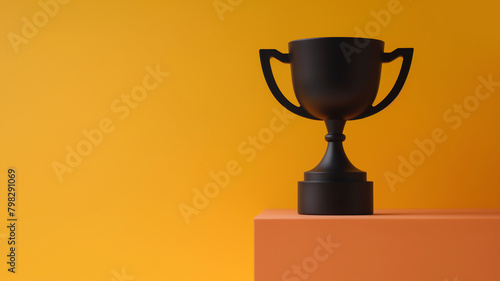 A matte black trophy cup on an orange pedestal with a vivid yellow-orange background. photo