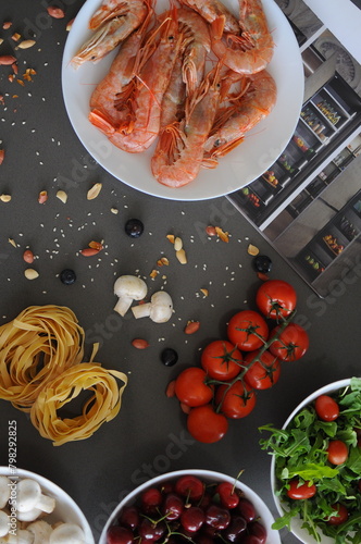 Spaghetti and fettuccine with ingredients for cooking pasta on wooden table with blank of round wooden kitchen board