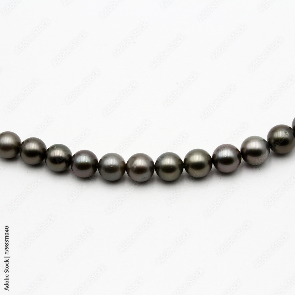 Expensive and luxurious Tahiti black pearls in a stylish necklace on white background, ready to be made into earrings, pendants, bracelets or a choker and sold in jewelry store. Expensive and luxurious Tahiti black pearls in a stylish necklace on white background, ready to be made into earrings, pendants, bracelets or a choker and sold in jewelry store.