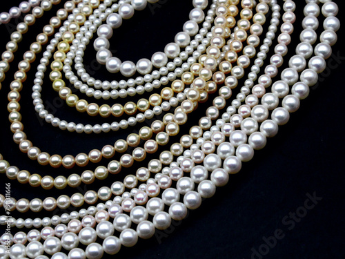 Expensive and luxurious Japanese saltwater Akoya pearls on strands of white, pink and golden organic gems ready to be made into necklaces and sold in jewelry store. photo