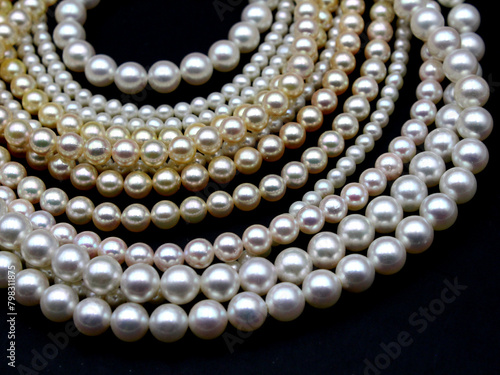 Expensive and luxurious Japanese saltwater Akoya pearls on strands of white, pink and golden organic gems ready to be made into necklaces and sold in jewelry store. photo