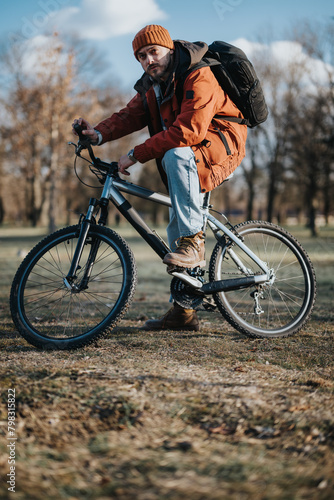 An active man in outdoor attire rides a mountain bike through a park setting during autumn.