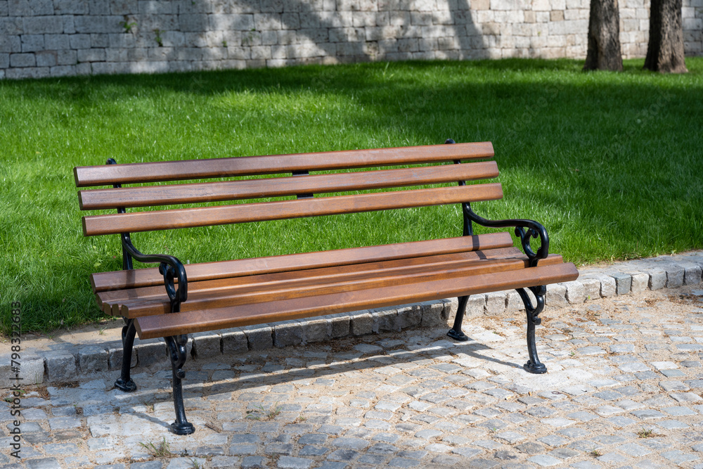 Brown benches for sitting in the city park surrounded by greenery and flowers. Benches for rest and relaxation. Brown benches for sitting in the city park surrounded by greenery and flowers. Benches for rest and relaxation.