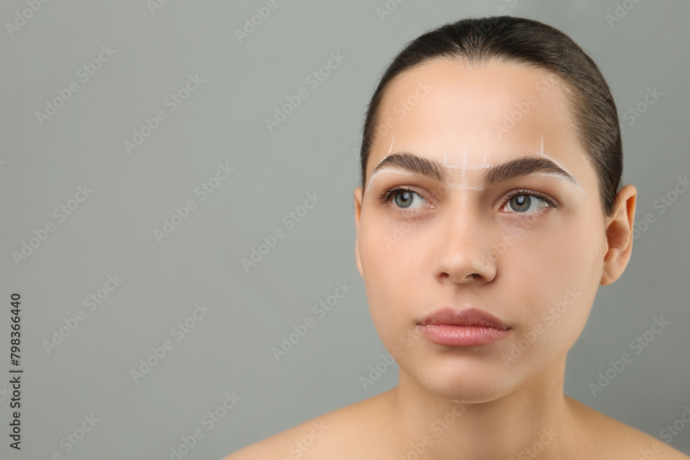 Eyebrow correction. Young woman with markings on face against grey background, space for text Eyebrow correction. Young woman with markings on face against grey background, space for text