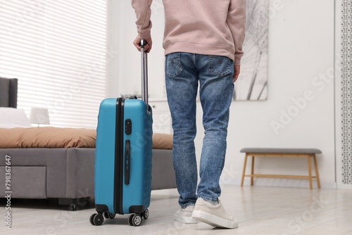 Guest with suitcase walking in hotel room, closeup