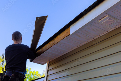 Master makes repairs in aftermath of hurricane, exposed wood was left after aluminum fascia trim was blown off photo