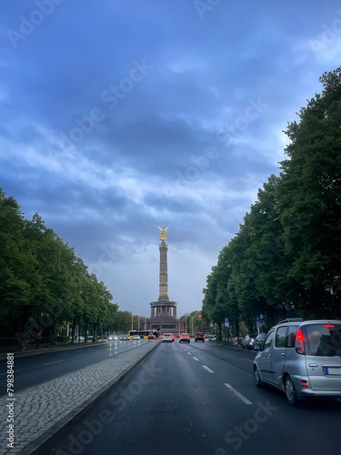 victory column on the avenue of 17 June in Berlin, at the blue hour in a day with stormy sky, a car in the foreground, vertical