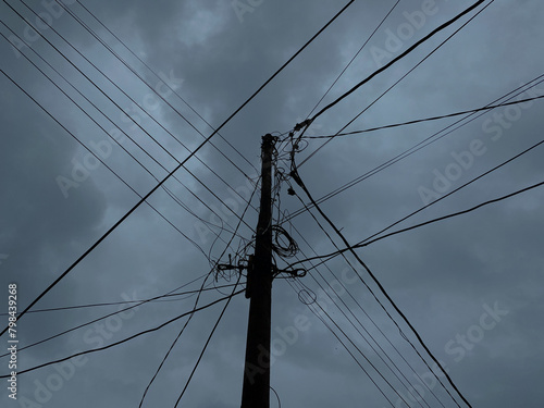 Power supply pole and cables, with dark cloudy sky background