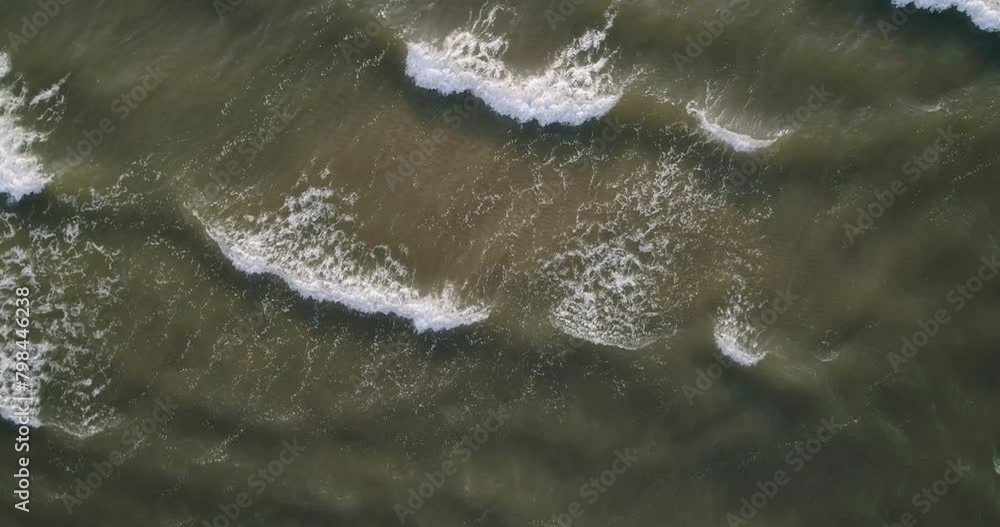 A body of water with waves crashing against the shore. The waves are white and the water is a dark color. Scene is calm and peaceful, as the waves gently lap against the shore A body of water with waves crashing against the shore. The waves are white and the water is a dark color. Scene is calm and peaceful, as the waves gently lap against the shore