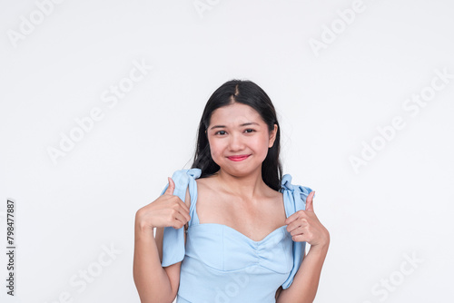 Young Asian woman in a powder blue dress giving a thumbs up, isolated on white background