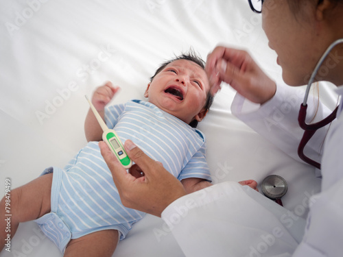 Baby illness medicine flu fever and thermometer, a doctor checks the temperature of the ill baby. Digital thermometer to measure the heat temperature of a sick child. Baby fever concept.
