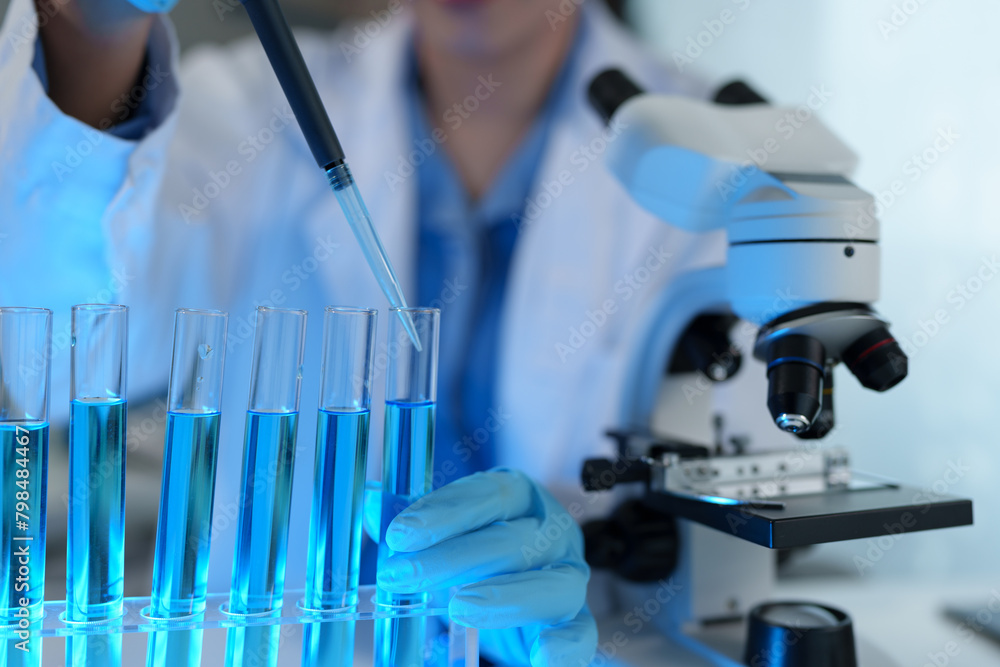 Scientist working in laboratory using micropipette Mixing liquid chemicals with genetically modified samples under a biotechnology microscope. Development of microbiology research experiment. Scientist working in laboratory using micropipette Mixing liquid chemicals with genetically modified samples under a biotechnology microscope. Development of microbiology research experiment.