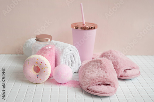 Fluffy pink slippers  bombs and bath salts on the tiled bathroom floor.